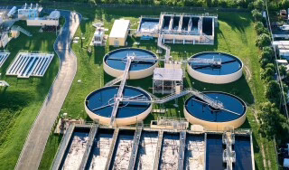Aerial view of a water treatment plant featuring circular clarification tanks and rectangular processing basins